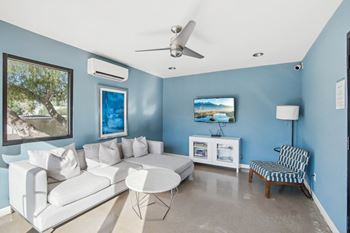 A living room with a white couch and a ceiling fan. at The Viridian Apartments, Scottsdale, Arizona